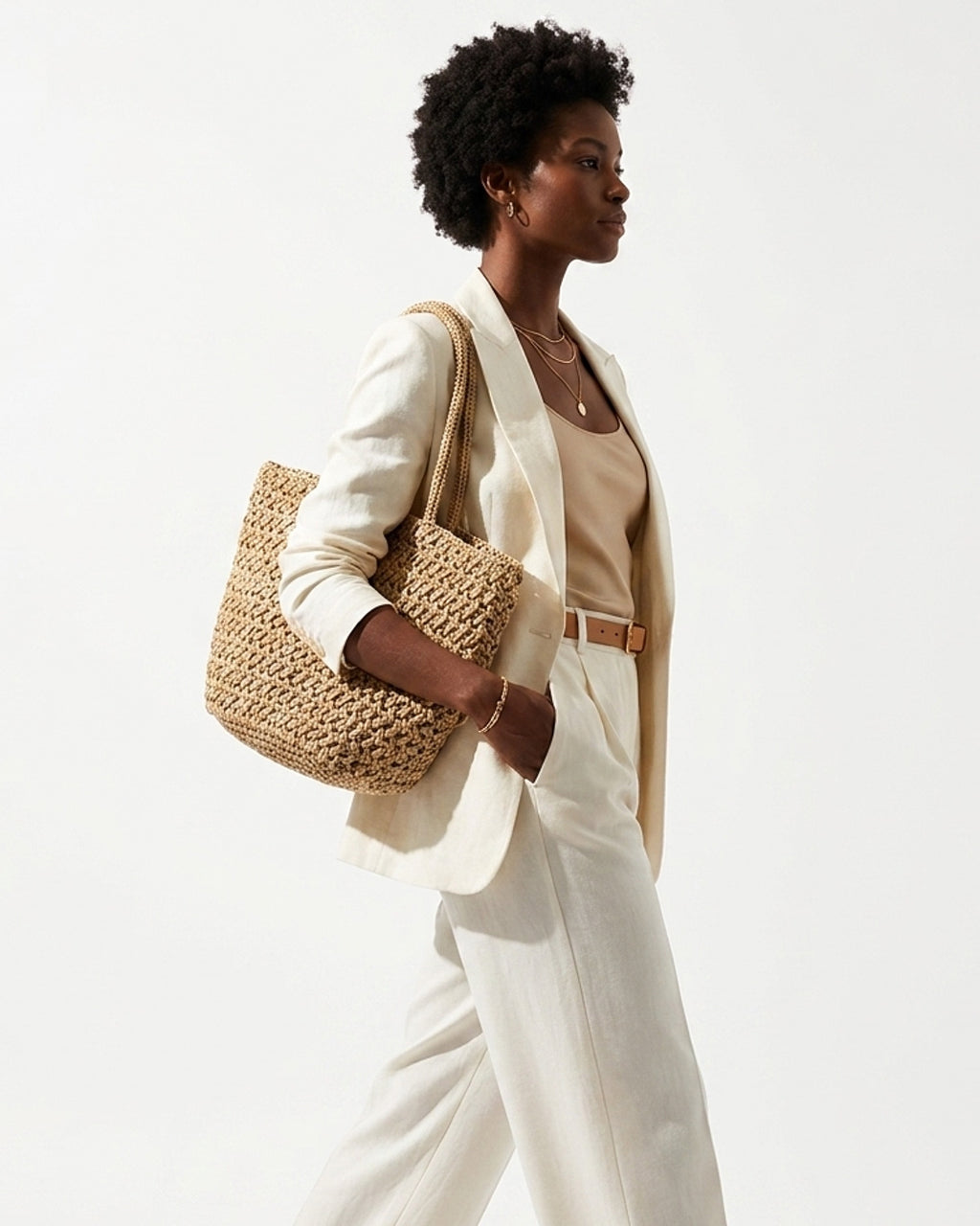 A stylish woman in a polished white-toned summer outfit carries a Natural Beige Woven Raffia Tote Bag with a Removable Pouch