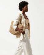 A stylish woman in a polished white-toned summer outfit carries a Natural Beige Woven Raffia Tote Bag with a Removable Pouch