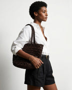 A woman in a stylish summer outfit carries a Natural Woven Raffia Tote Bag with Removable Pouch, Coffee color