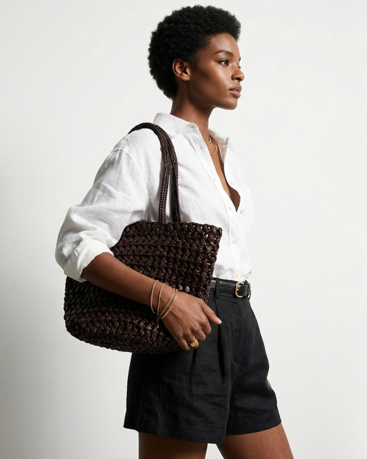 A woman in a stylish summer outfit carries a Natural Woven Raffia Tote Bag with Removable Pouch, Coffee color