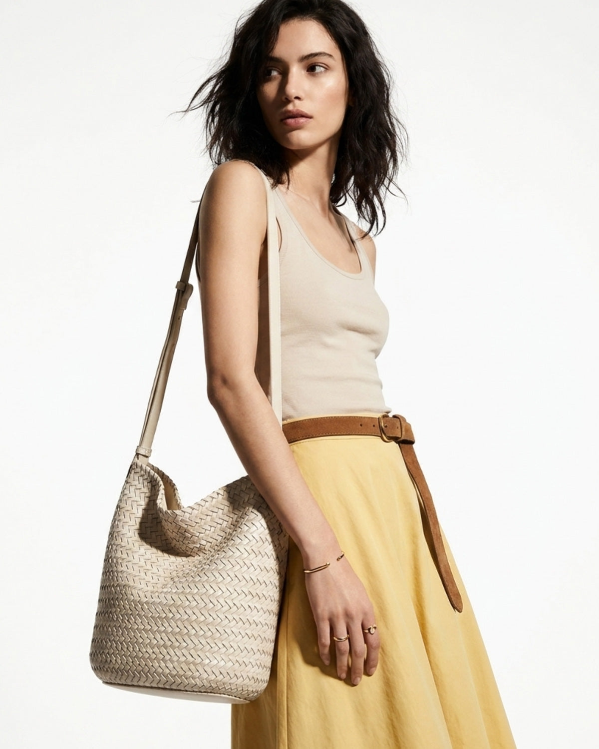 Chic woman in a stylish casual outfit with a white woven vegan leather bucket bag with an adjustable strap