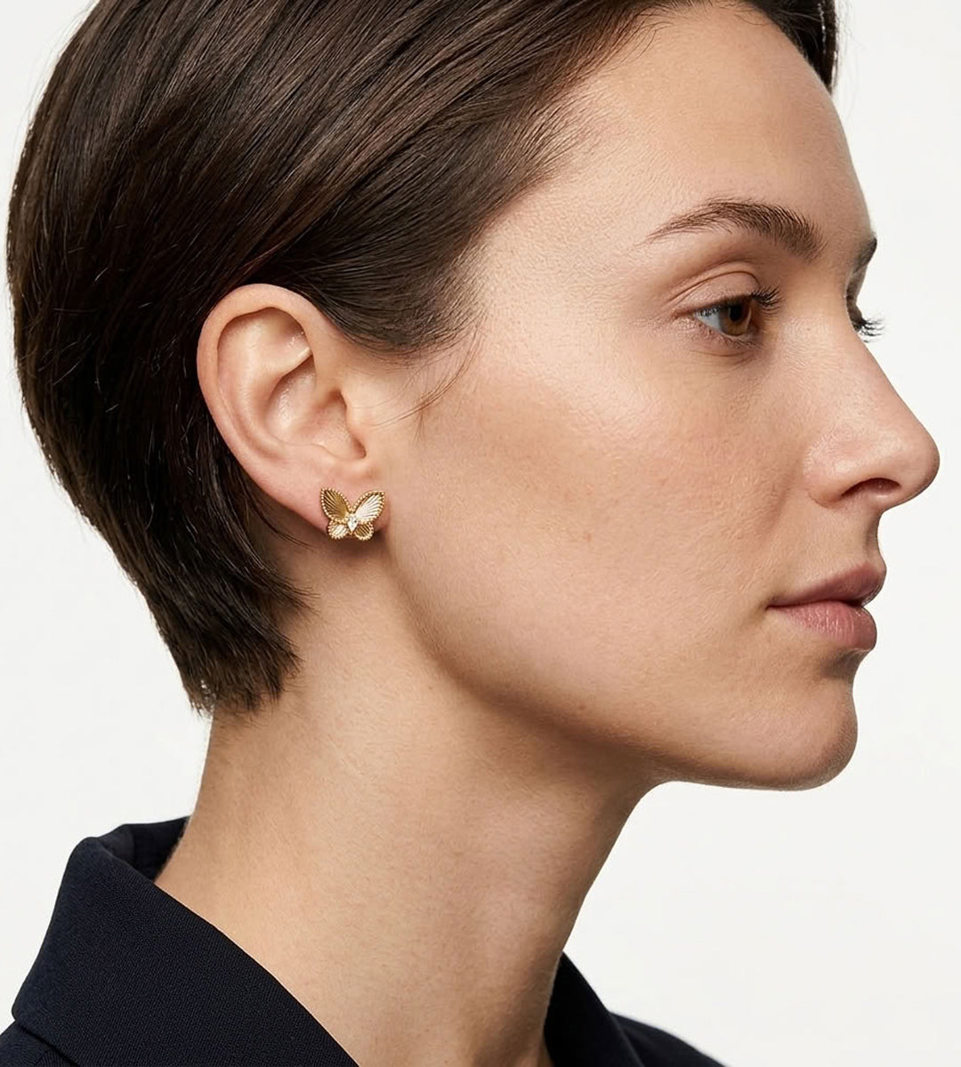 Close-up of a model wearing a Vintage Gold butterfly stud earring with textured wings and cubic zirconia accents.