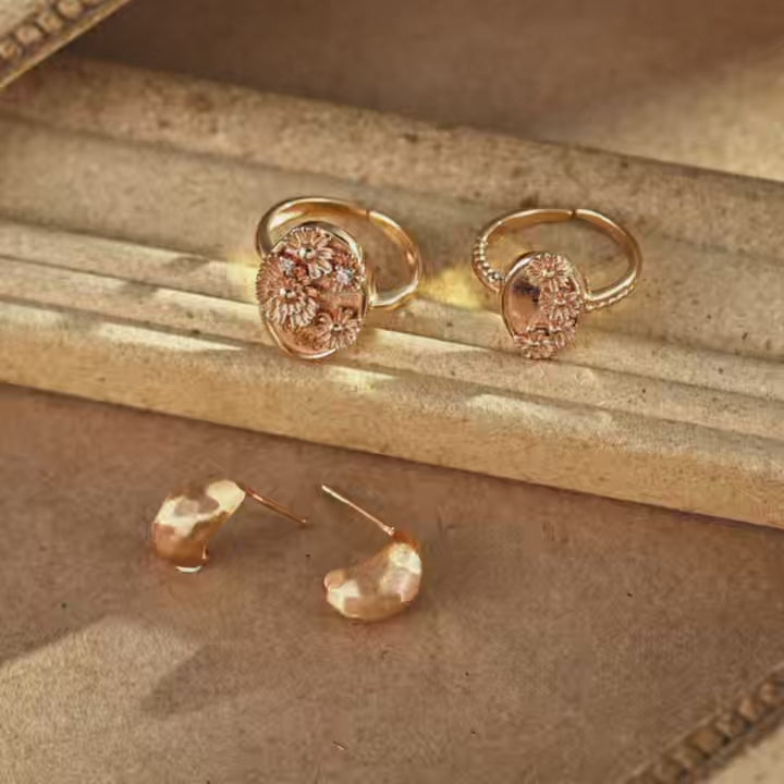 Sunny Daisy gold-plated open ring with an oval face, raised daisy flowers and sparkling accents, displayed on a vintage-style jewellery tray.