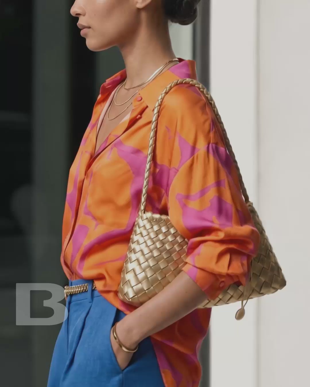Four models walk sequentially down a sunlit city sidewalk, one after another, each carrying a Woven Shoulder Bag in one of four colors. The camera focus is on the luxurious outfits and Woven Shoulder Bags.