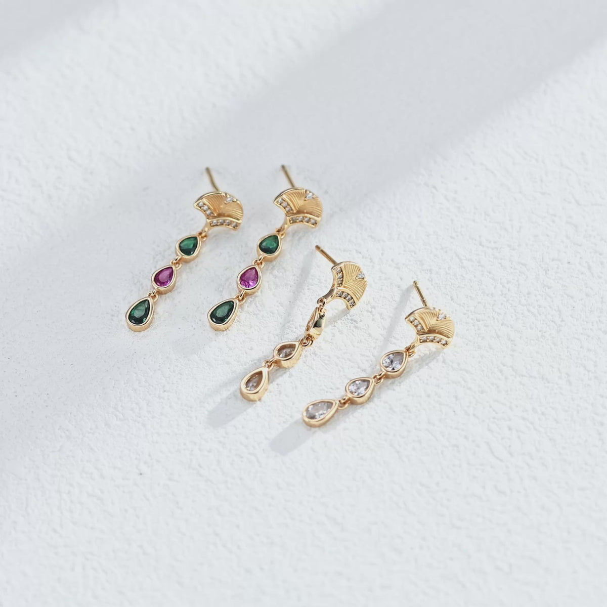 Video of a pair of an 18K Gold Plated S925 Silver Art Deco Fan Stud Teardrop Drop Earrings accented with Clear, Burgundy and Green Cubic Zirconia stones
