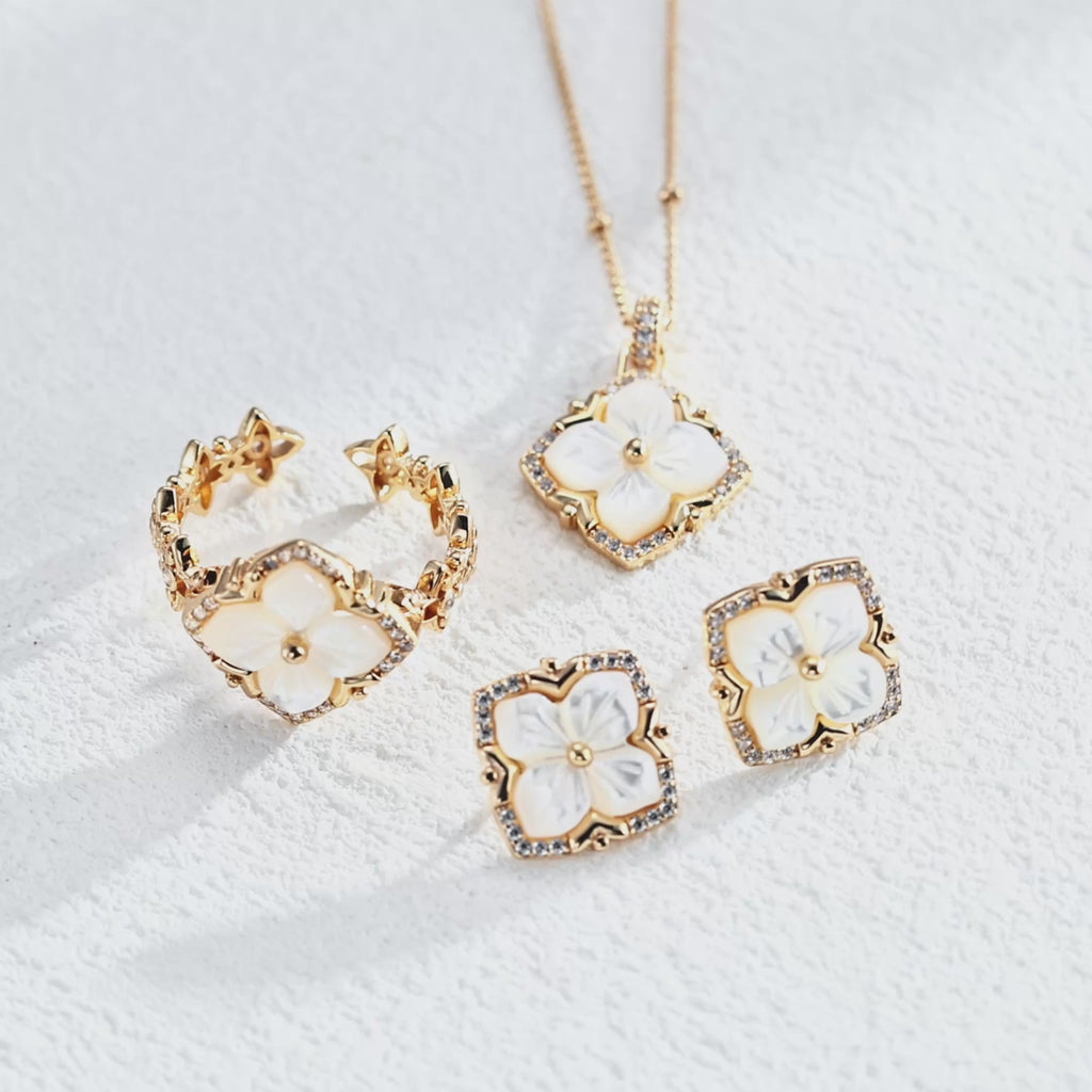 A video of a jewelry set of 18K White Gold Plated S925 Silver floral stud earrings with white mother-of-pearl flower centers and cubic zirconia halos, matching necklace and open ring