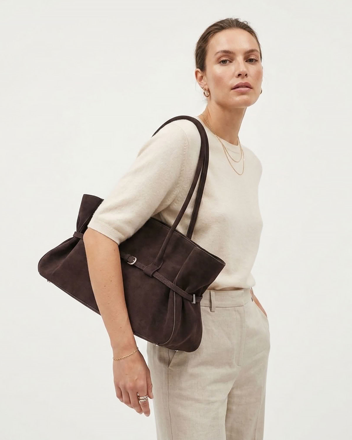 A woman in a stylish light-toned outfit carries a Frosted Brown Structured Shoulder Tote with Buckle Strap | BUCKLE Collective