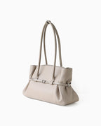 A structured taupe genuine leather tote handbag with a double top handle, gathered side details, and a central strap with a silver buckle | BUCKLE Collective